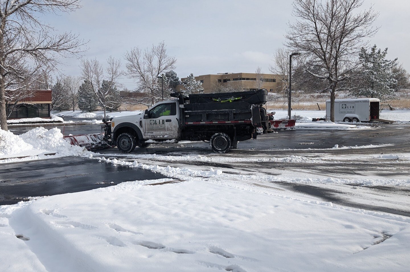 snow plow truck removing snow from parking lot putting in piles